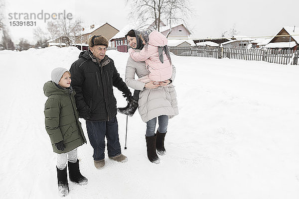 Grossvater zusammen mit Tochter und Enkelkindern im Schnee