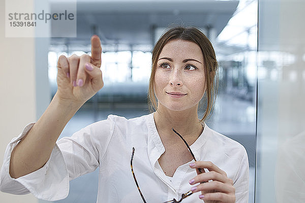 Junge Geschäftsfrau berührt virtuellen Touchscreen