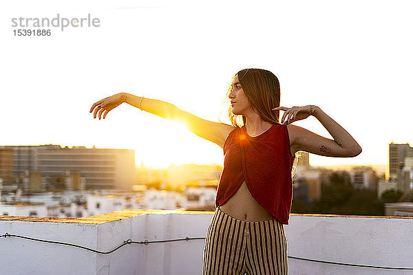 Anmutiges Teenager-Mädchen bewegt sich bei Sonnenuntergang auf der Dachterrasse in der Stadt