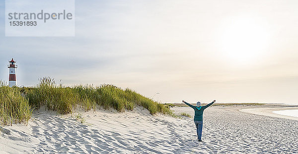 Deutschland  Sylt  Nordsee  glückliche Frau beim Spaziergang am Sandstrand