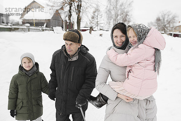 Großvater spaziert mit Tochter und Enkelkindern im Winter
