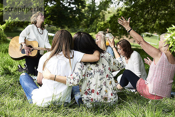 Frauengruppe mit Gitarre amüsiert sich bei einem Picknick im Park