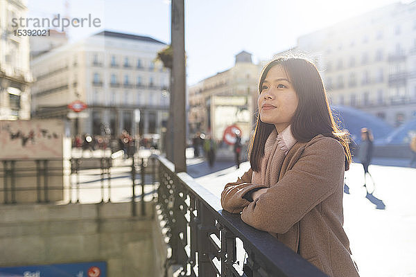 Spanien  Madrid  lächelnde junge Frau an der Puerta del Sol schaut sich um