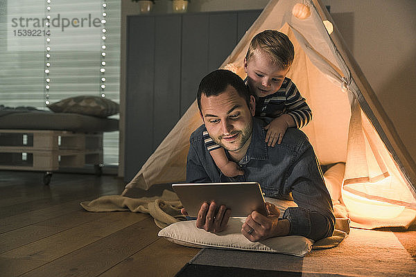 Vater und Sohn teilen sich eine Tafel in einem beleuchteten Zelt zu Hause
