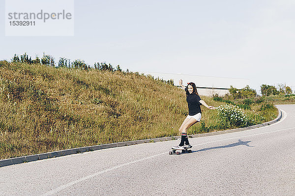 Spanien  Teenagerin auf Skateboard eine Straße entlang