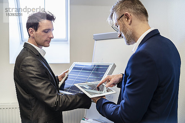 Zwei Geschäftsleute mit Solarzelle und Tablet im Amt