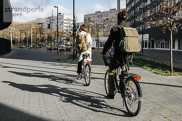 Ein Paar fährt E-Bikes in der Stadt  Rückansicht