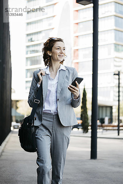 Geschäftsfrau mit Smartphone  die in der Stadt pendelt