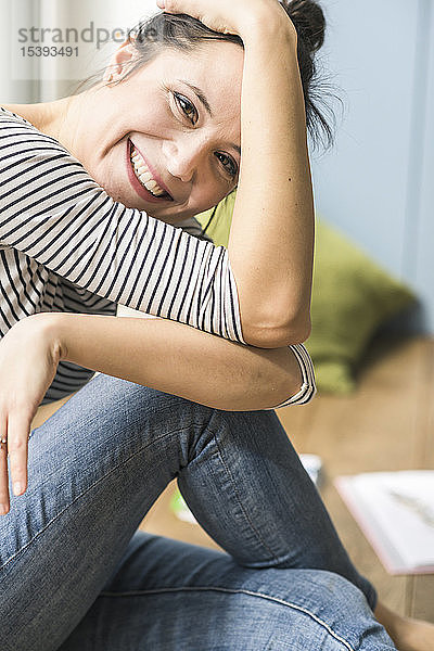 Porträt einer glücklichen Frau  die zu Hause auf dem Boden sitzt