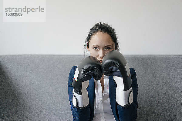 Porträt einer jungen Frau auf Couch mit Boxhandschuhen