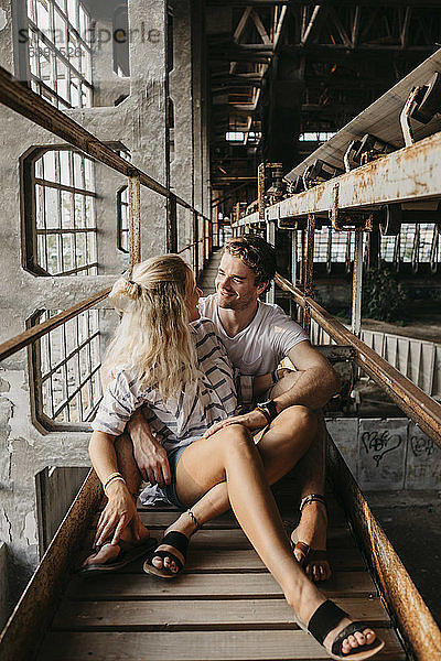 Glückliches junges Paar sitzt in einem alten Bahnhof