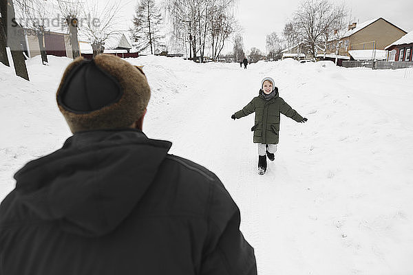Glücklicher Enkel läuft im Winter zu seinem Großvater