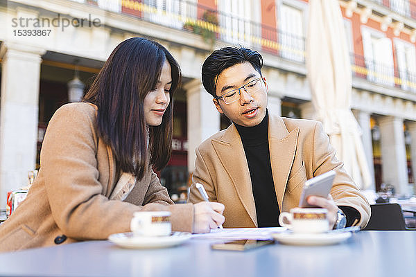 Spanien  Madrid  junges Paar telefoniert und macht Notizen in einem Café auf der Plaza Mayor