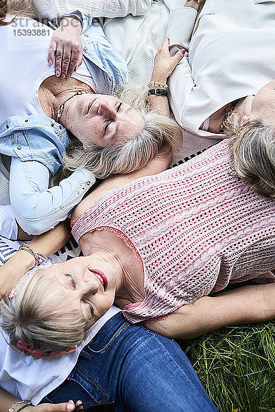 Draufsicht auf eine Gruppe älterer Frauen  die auf einer Wiese liegen