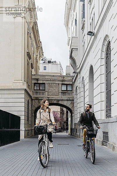 Lächelndes Paar fährt E-Bikes in der Stadt