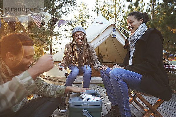 Glückliche Freunde spielen Karten auf dem Campingplatz
