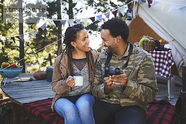 Verliebtes junges Paar mit Fernglas beim Kaffeetrinken auf dem Campingplatz