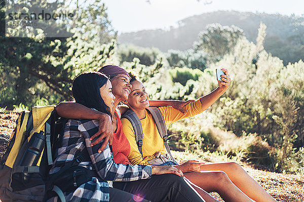 Glückliche Mutter und Töchter machen ein Selfie  wandern im sonnigen Wald