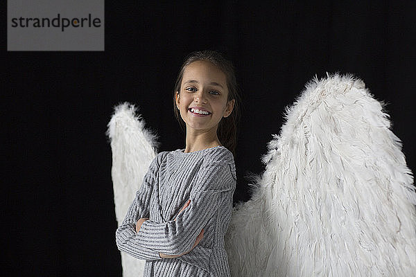 Porträt lächelndes  selbstbewusstes Mädchen mit Engelsflügeln