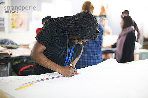 Fokussierte Modedesignerin beim Zeichnen von Nähmustern im Atelier