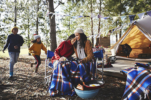 Glückliches  liebevolles lesbisches Paar mit Kindern entspannt auf einem Campingplatz im Wald