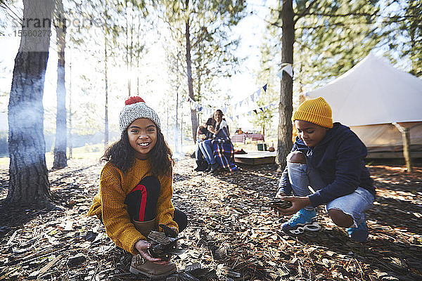 Porträt eines lächelnden Mädchens  das auf einem sonnigen Zeltplatz im Wald Holz sammelt