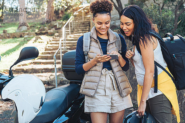 Junge Frauen Freunde mit Smartphone auf Motorroller