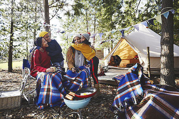Glückliches  liebevolles lesbisches Paar und Kinder entspannen sich auf einem Campingplatz im Wald