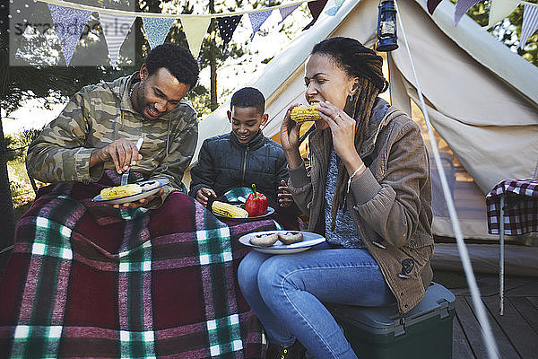 Familie isst Maiskolben auf dem Campingplatz