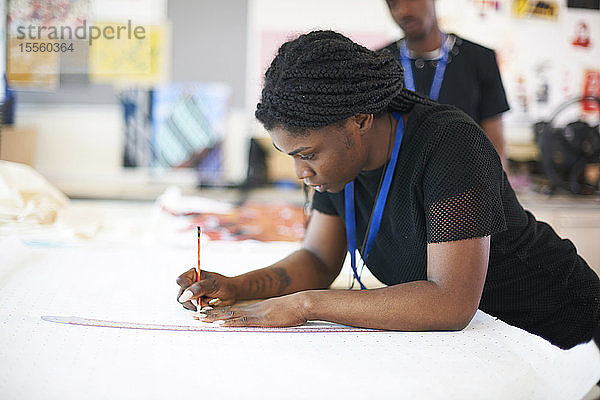 Fokussierte Modedesignerin beim Zeichnen von Nähmustern im Atelier