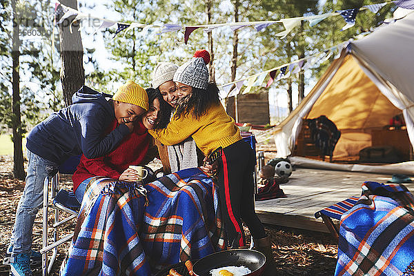 Glückliches  zärtliches lesbisches Paar und Kinder  die sich auf dem Campingplatz umarmen