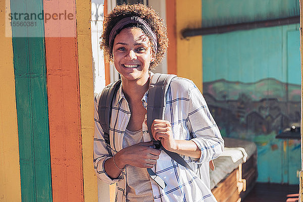 Porträt lächelnde  selbstbewusste junge Frau auf sonniger Veranda