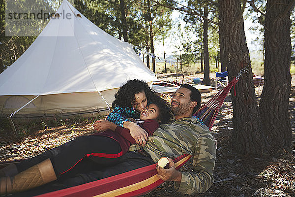 Glückliche  sorglose Familie entspannt sich in der Hängematte auf einem Campingplatz im Wald