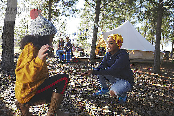 Verspielter Bruder zeigt seiner Schwester auf dem Campingplatz im Wald einen Laubfrosch