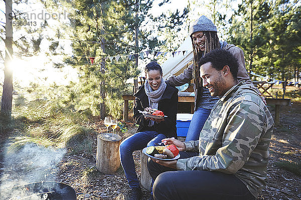 Glückliche Freunde beim Essen auf dem sonnigen Campingplatz