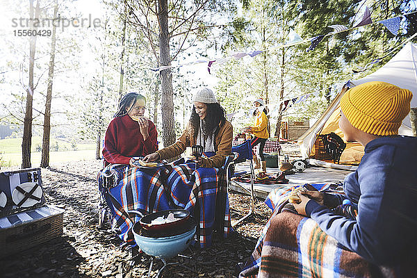 Lesbisches Paar und Kinder essen auf einem sonnigen Campingplatz
