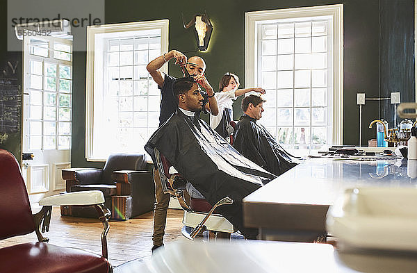 Männlicher Friseur  der einem Kunden im Friseursalon die Haare schneidet