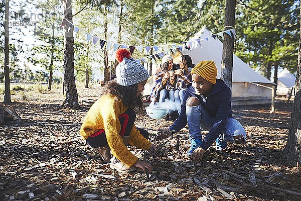 Bruder und Schwester sammeln Brennholz auf einem Campingplatz im Wald