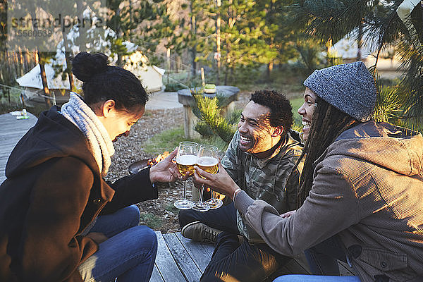 Glückliche Freunde stoßen mit Weingläsern auf einem Campingplatz im Wald an