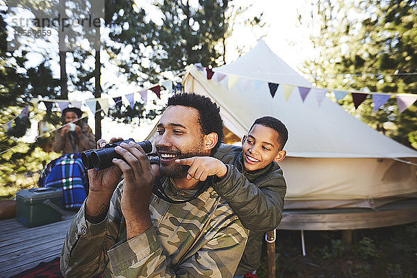 Glücklicher  neugieriger Vater und Sohn mit Fernglas auf dem Campingplatz