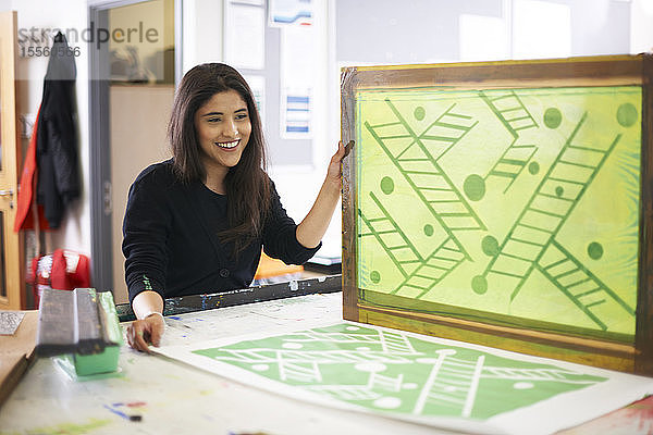 Lächelnde Kunststudentin beim Siebdruck im Kunstatelier