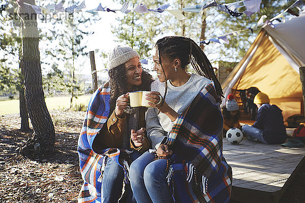 Glückliches lesbisches Paar  das sich auf einem sonnigen Campingplatz entspannt und Kaffee trinkt