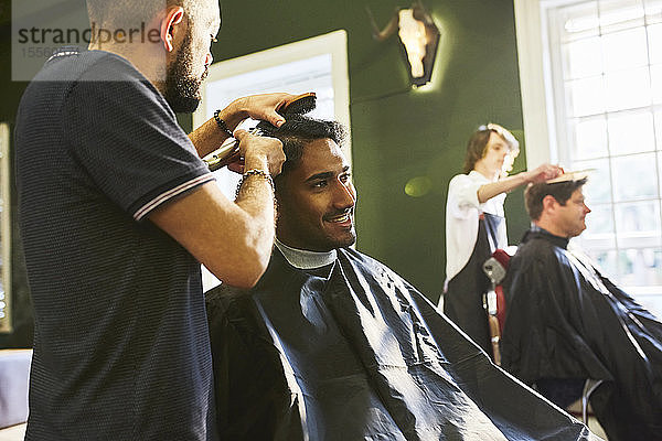 Lächelnder Mann erhält Haarschnitt beim Friseur