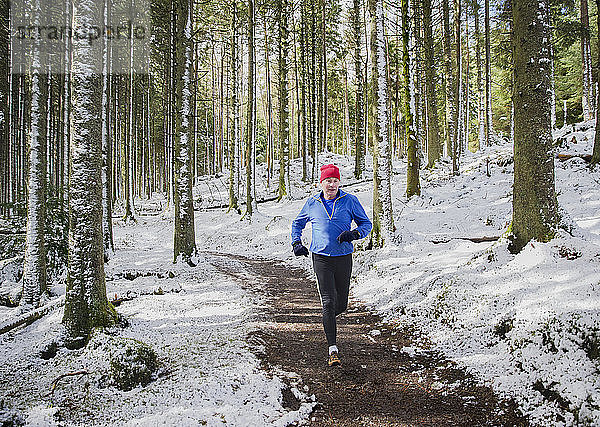 Älterer Mann joggt im verschneiten Wald