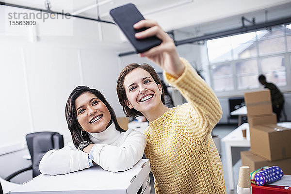 Lächelnde Geschäftsfrauen machen ein Selfie im neuen Büro