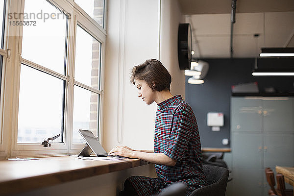 Geschäftsfrau arbeitet an digitaler Tafel im Bürofenster