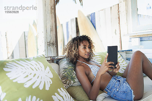 Junge Frau benutzt digitales Tablet auf einer Strandterrasse