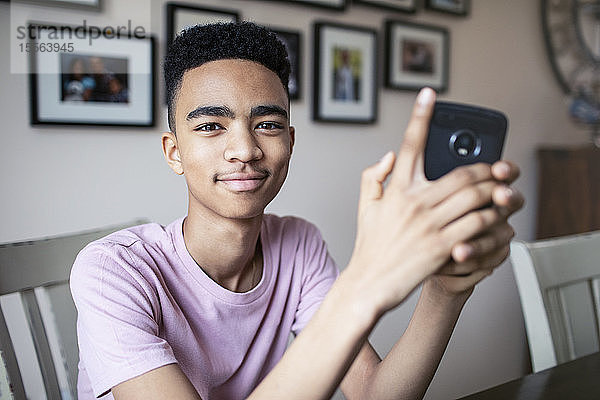 Porträt eines selbstbewussten Teenagers  der ein Smartphone benutzt