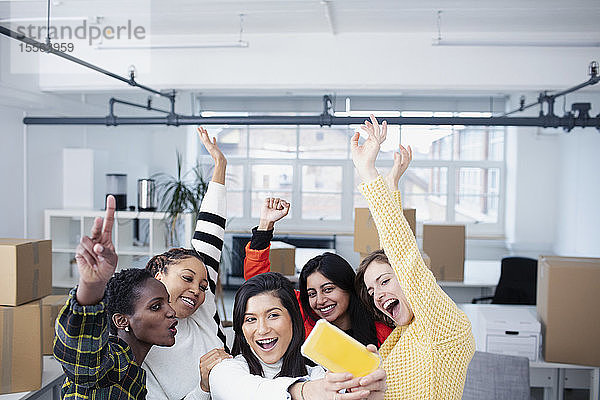 Glückliche Geschäftsfrauen feiern ihr neues Büro und machen ein Selfie