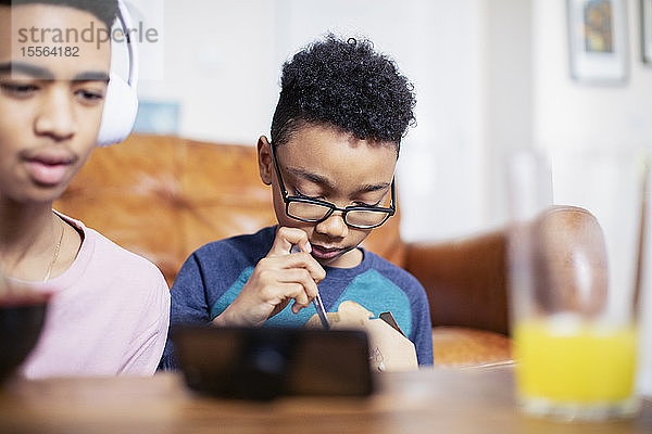 Brüder essen und benutzen ihr Smartphone